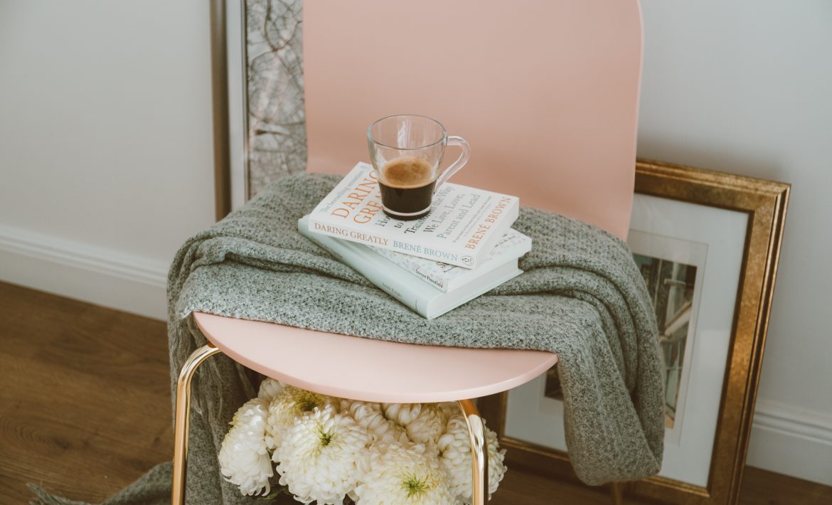 Practice Self-Care: Pink chair with throw, book and cup of coffee.