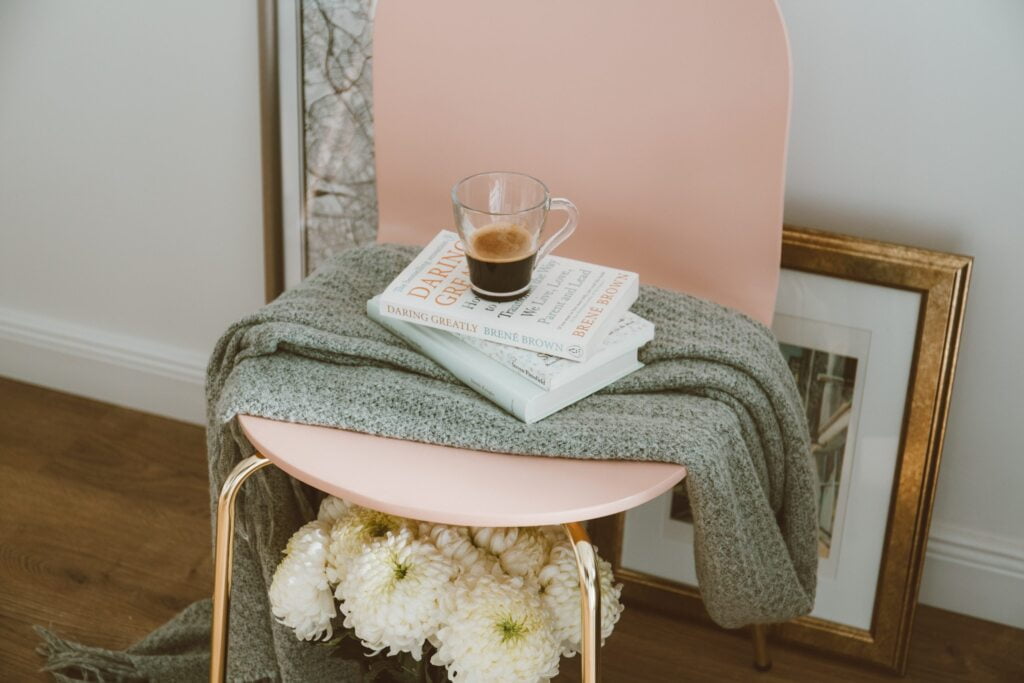 Practice Self-Care: Pink chair with throw, book and cup of coffee.
