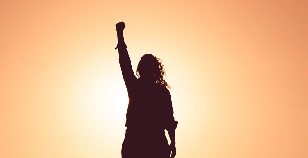 Knowing your power - Silhouette of woman standing with fist in the air