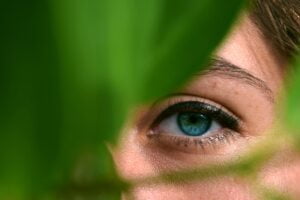 Clarity Woman's eye shown behind plant