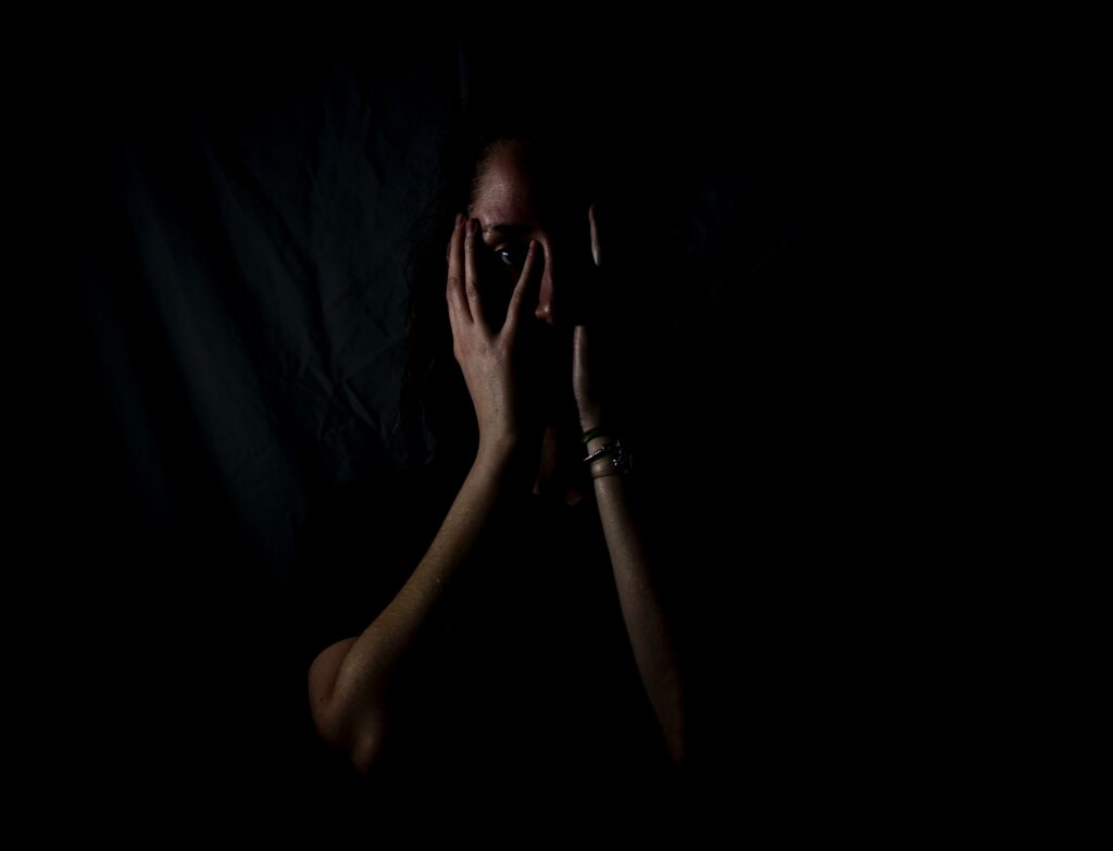Fear - Woman in darkness with hands over her face