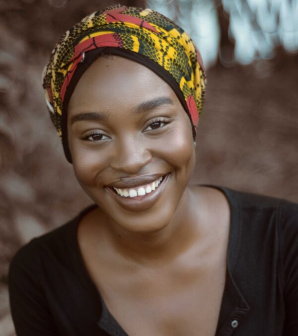Headshot of confident woman dressed in black with headscarf smiling brightly
